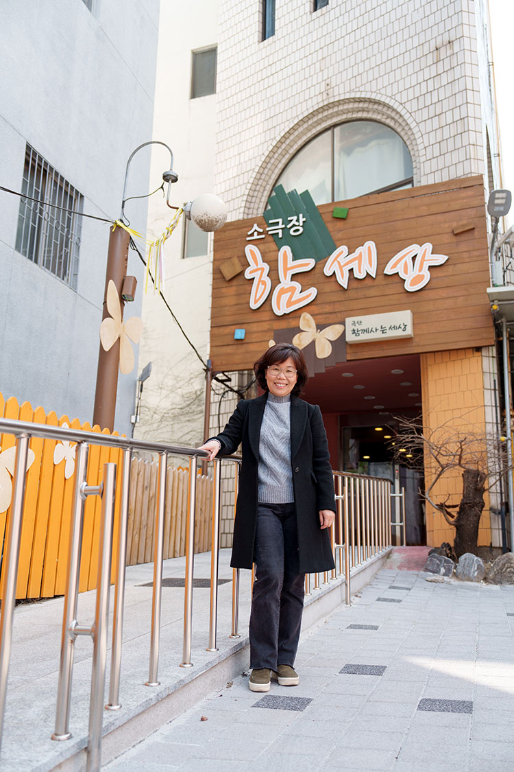 휠체어 사용자의 접근이 가능한 소극장 함세상 앞에서 박연희 씨가 미소 짓고 있다.