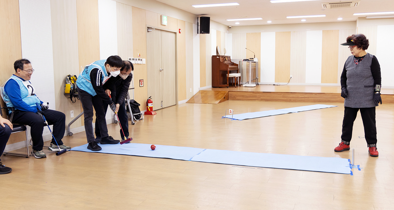  비가 와 충현복지관 강당에서 게이트볼을 하는 회원들