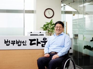 이성준 변호사가 법무법인 다움 글이 새겨진 사무실을 배경으로 정면을 바라보며 미소짓는 모습