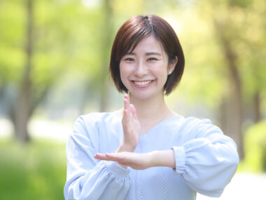 단발머리를 한 여성이 미소를 지으며 감사합니다의 뜻인 수어 동작을 하고 있는 사진