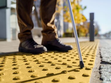 흰 지팡이를 든 시각장애인이 유도 블록으로 걸어가는 사진